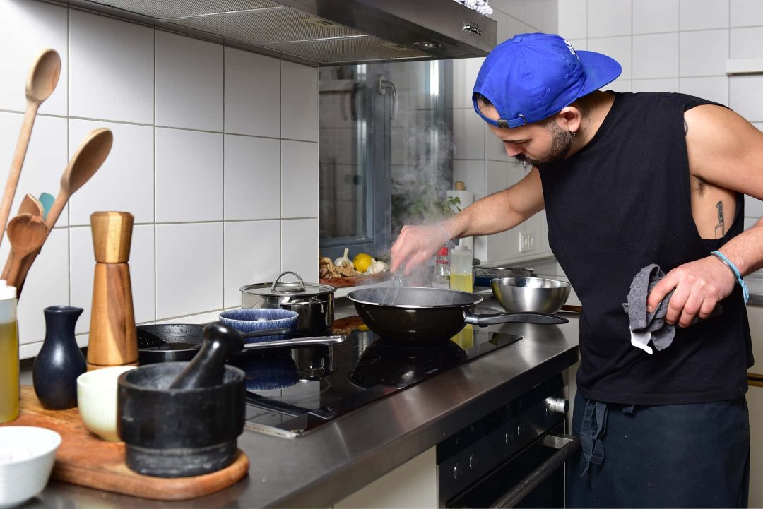 Koch bei der Zubereitung des Lomo Saltado in der Kueche